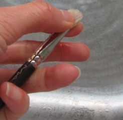 LIghtly squeezing excess liquid out of brush